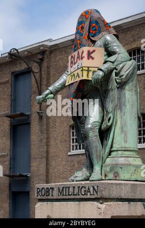 Ore prima che fosse rimossa dalla fondazione Canal and River Trust, la statua del mercante di schiavi, Robert Milligan si trova coperto da attivisti della materia Black Lives fuori dal Museo dei Docklands di Londra sul West India Quay, un tempo il magazzino più lungo del mondo pagato dai profitti della schiavitù, il 9 giugno 2020, A Londra, Inghilterra. Dopo le proteste di George Floyd negli Stati Uniti e nel Regno Unito Black Lives, i gruppi che chiedono la rimozione di statue e nomi di strada con collegamenti al commercio degli schiavi, Milligan e altre statue di profitatori della schiavitù britannica, sono diventati un punto di protesta. Foto Stock