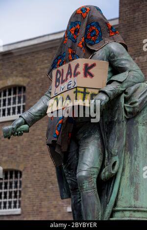 Ore prima che fosse rimossa dalla fondazione Canal and River Trust, la statua del mercante di schiavi, Robert Milligan si trova coperto da attivisti della materia Black Lives fuori dal Museo dei Docklands di Londra sul West India Quay, un tempo il magazzino più lungo del mondo pagato dai profitti della schiavitù, il 9 giugno 2020, A Londra, Inghilterra. Dopo le proteste di George Floyd negli Stati Uniti e nel Regno Unito Black Lives, i gruppi che chiedono la rimozione di statue e nomi di strada con collegamenti al commercio degli schiavi, Milligan e altre statue di profitatori della schiavitù britannica, sono diventati un punto di protesta. Foto Stock