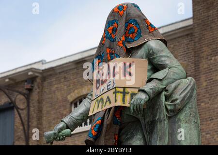 Ore prima che fosse rimossa dalla fondazione Canal and River Trust, la statua del mercante di schiavi, Robert Milligan si trova coperto da attivisti della materia Black Lives fuori dal Museo dei Docklands di Londra sul West India Quay, un tempo il magazzino più lungo del mondo pagato dai profitti della schiavitù, il 9 giugno 2020, A Londra, Inghilterra. Dopo le proteste di George Floyd negli Stati Uniti e nel Regno Unito Black Lives, i gruppi che chiedono la rimozione di statue e nomi di strada con collegamenti al commercio degli schiavi, Milligan e altre statue di profitatori della schiavitù britannica, sono diventati un punto di protesta. Foto Stock