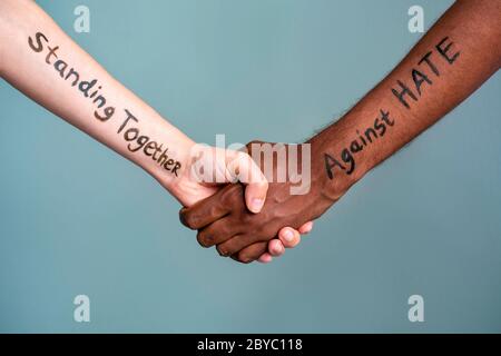 Stretta di mano tra la donna umana bianca e nera e le mani maschili con testo del messaggio stare insieme contro L'ODIO. Il concetto di Black Lives è una protesta Foto Stock