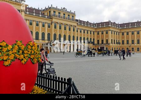 All'esterno del Palazzo Schonbrunn di Vienna, in Austria, sono presenti carrozze trainate da cavalli e una grande piantatrice di uova pasquali che festeggia le vacanze primaverili. Foto Stock