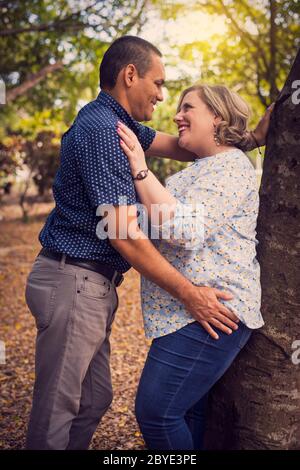 Bella coppia baciando e tenendo le mani che camminano nel legno Foto Stock