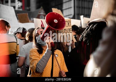 La giovane donna grida al megafono per protesta Foto Stock