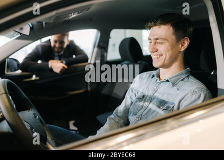 Assistente professionale di vendita che mostra la nuova auto al cliente nella concessionaria auto. Foto Stock