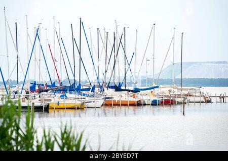 Mardorf, Germania. 09 giugno 2020. Le barche a vela sono ormeggiate presso un molo sulla riva nord dello Steinhuder Meer. Sullo sfondo è possibile vedere la discarica di potassio dalla miniera Sigmundwall di Wunstorf-Bokeloh. Credit: Hauke-Christian Dittrich/dpa/Alamy Live News Foto Stock