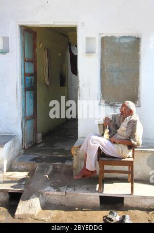 L'anziano indiano si siede fuori casa Foto Stock