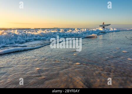 Surfista della Florida a Jacksonville Beach in una colorata mattinata all'alba. (STATI UNITI) Foto Stock