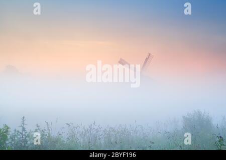 mulino a vento in nebbia densa all'alba Foto Stock