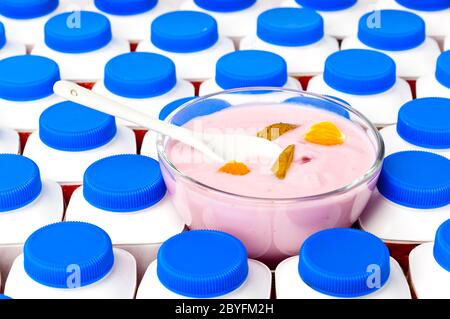 Bottiglie di yogurt con coperchi blu scuro e un bicchiere b Foto Stock