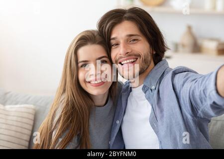 Coppia innamorata che prende selfie mentre si siede sul divano Foto Stock