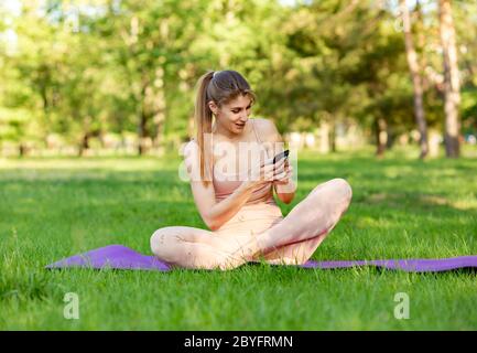 Donna che fa yoga e guarda i tutorial online su smartphone Foto Stock