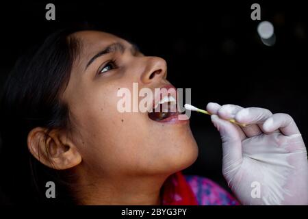 Mano del medico che prende il test della saliva dalla bocca della giovane donna con il tampone di cotone. Prelievo del campione di Coronavirus Throat. Viste ravvicinate. Foto Stock