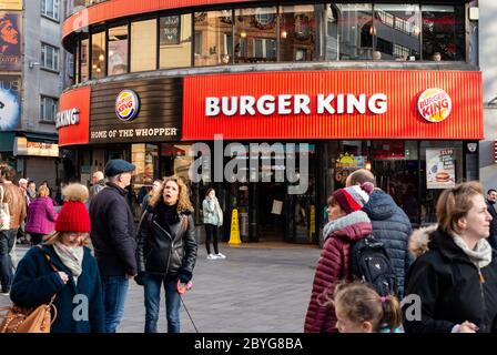 Affaccendato vista urbana di persone e turisti fuori Burger King fast food ristorante outlet facciata rossa in Leicester Square West End Londra il giorno di sole Foto Stock