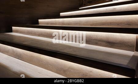 Scala illuminata con scalini in legno e illuminata di notte all'interno di una grande casa. Foto Stock