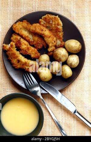 Foto di patate bollite e strisce di pesce croccanti fritte su un piatto. Foto Stock