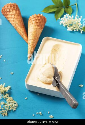 Gelato artigianale dolce di fiori di sambuco in una piccola muffa metallica con coni di waffle e scooper rustico. Messa a fuoco selettiva. Foto Stock