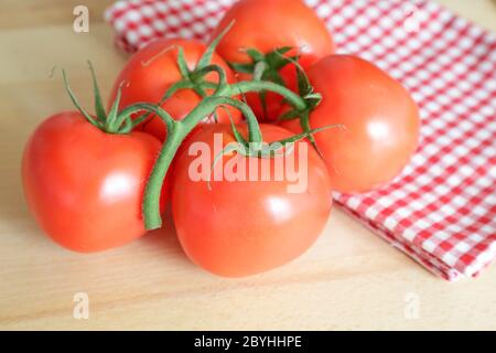 Pomodori chiamati grappolo tipo su tavola di legno, luce naturale Foto Stock