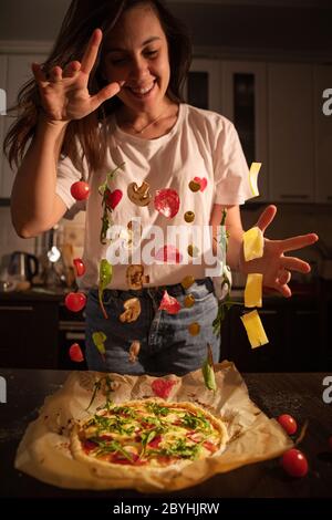 donna che fa ingredienti pizza come funghi salumi formaggio di oliva congelare in aria Foto Stock