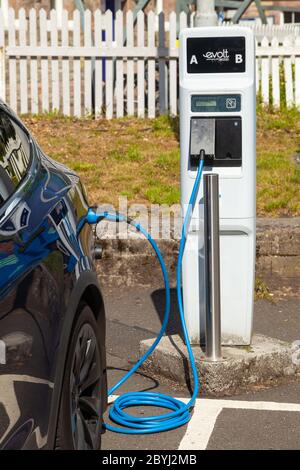 Un'auto elettrica Tesla in carica presso una stazione di ricarica pubblica ad Aberdour, Fife, Scozia Foto Stock
