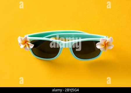 Occhiali da sole con fiori su sfondo giallo Foto Stock