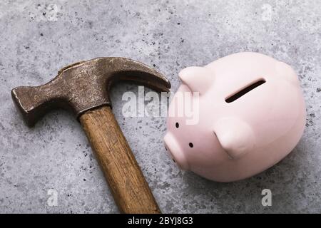 Banco di porcellini rosa e martello sul tavolo, primo piano. Concetto di crisi Foto Stock