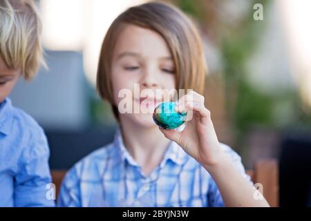 Bambini dolci, fratelli, uova da colorare e da pastare per Pasqua in giardino, all'aperto a casa in cortile Foto Stock