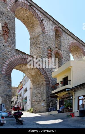 Kavala, Grecia - 13 giugno 2019: L'uomo non identificato legge il giornale di fronte ad un caffè situato all'acquedotto medievale di Kamares Foto Stock