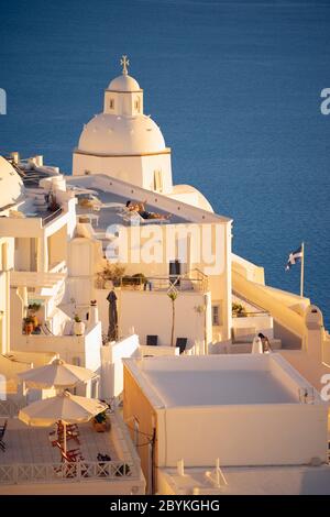 Tramonto su Thira sull'isola greca di Santorini, con una tipica cappella a cupola bianca sullo sfondo Foto Stock