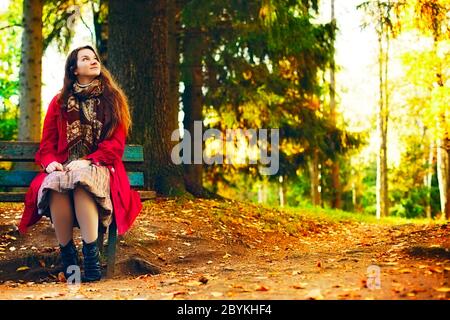 Giovane donna elegante seduta su panca Foto Stock