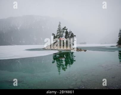 Bella giornata invernale all'Eibsee vicino grainau al monte zugspitze, riflesso dell'isola Braxeninsel in inverno Foto Stock