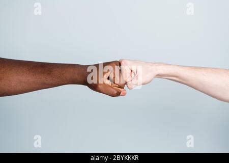 Closeup foto di due armi diversi colori della pelle di razza amici multinazionali antirazzismo problema aiutare insieme amici mondo globo integrazione dando pugni Foto Stock
