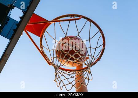 Street basket slam dunk concorrenza. Primo piano della palla che cade nel cerchio. Gioco urbano giovanile. Concetto di successo, punteggio e vincita Foto Stock