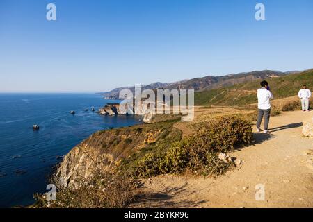 I turisti posano per le foto, sull'Oceano Pacifico, sulla aspra California vicino al ponte di Bixby Creek. Autostrada CA1, Pacific Coast Highway. Stati Uniti d'Ame Foto Stock