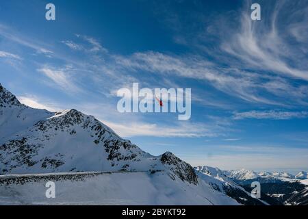 Elicottero di soccorso rosso che sorvola la vista delle rocce innevate nella località sciistica alpina di Zermatt vicino al monte Cervino. Paesaggio naturale invernale della Svizzera Foto Stock