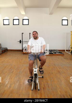 uomo in sovrappeso su simulatore di bicicletta Foto Stock