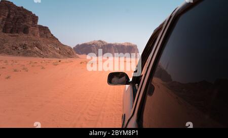 Jeep fuoristrada che attraversa l'incredibile paesaggio lunare nel villaggio di Wadi Rum nel deserto di sabbia rossa giordano. Wadi Rum conosciuta anche come la Valle Foto Stock