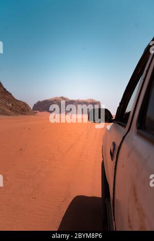 Jeep fuoristrada che attraversa l'incredibile paesaggio lunare nel villaggio di Wadi Rum nel deserto di sabbia rossa giordano. Wadi Rum conosciuta anche come la Valle Foto Stock