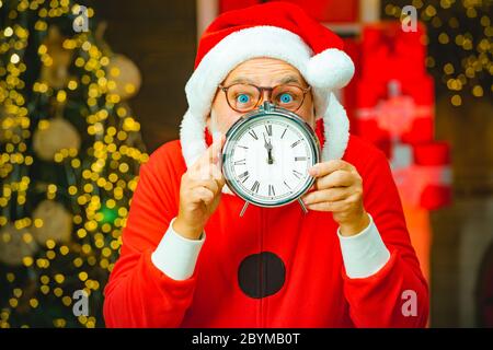 Babbo Natale - anziano bearded divertente. Foto di Santa che indica l'orologio che mostra cinque minuti fino a mezzanotte. Tempo di Natale. Anno nuovo e Natale Foto Stock