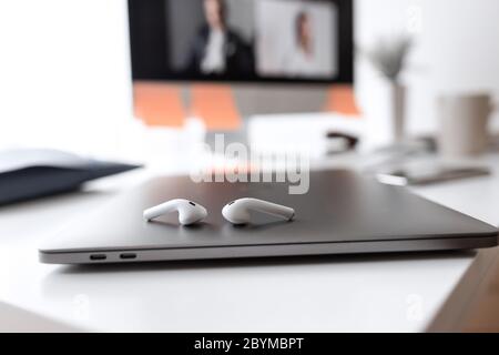 Smartphone con videochiamata e cuffie su un desktop grigio. Vista dall'alto. Foto Stock