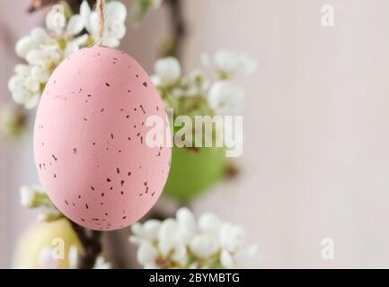 Uova di Pasqua appese sul ramo fiorente dell'albero di mela. Arredamento festivo Foto Stock