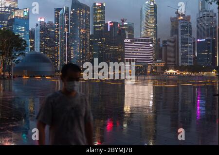 28.05.2020, Singapore, , Singapore - lo skyline con i grattacieli del quartiere degli affari in Marina Bay si riflette in pozzanghere lungo la promena Foto Stock