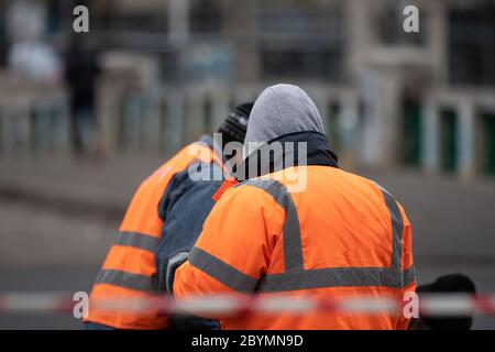 Vista posteriore di un addetto alle costruzioni che indossa una giacca riflettente sporca che si prepara al lavoro. Bucarest, Romania, 2020 Foto Stock