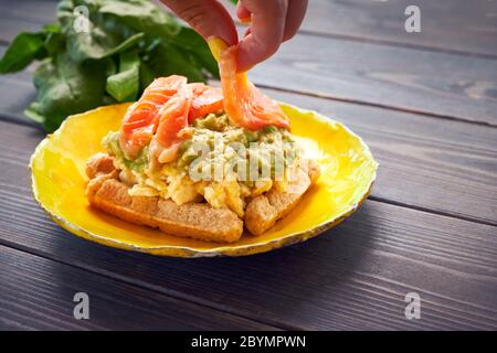 Waffle belgi con uova strapazzate, avocado e salmone su tavola di legno. Piatto, pancetta. Variazione colazione keto Foto Stock