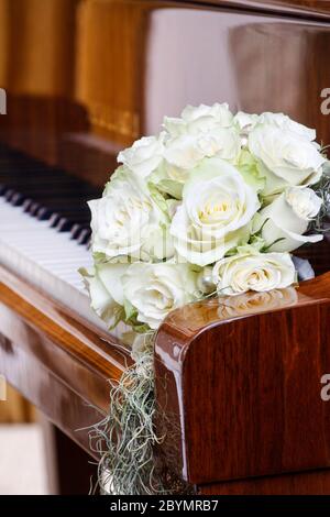 Bouquet di rose bianche che si stenderà sulle chiavi del pianoforte. Decorazioni per feste Foto Stock