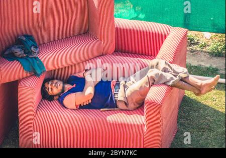 Udaipur, India - 10 Febbraio 2014 - uomo indiano che dorme e riposa su poltrona all'aperto Foto Stock