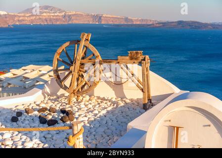 La vecchia ruota girevole abbellimento per un hotel nella città di Oia, sull'isola greca di Santorini e oltre è il Mar Egeo. Foto Stock