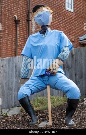 Sentiero o festival dello Scarecrow, parte delle celebrazioni del carnevale Old Basing, Hampshire, Regno Unito. Scarecrow vestito da operaio ospedaliero con maschera facciale. Foto Stock