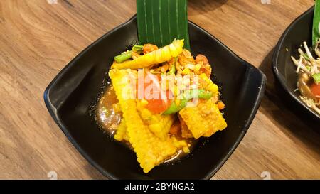 insalata di mais con vermicelli e granchio salato su piatto nero Foto Stock