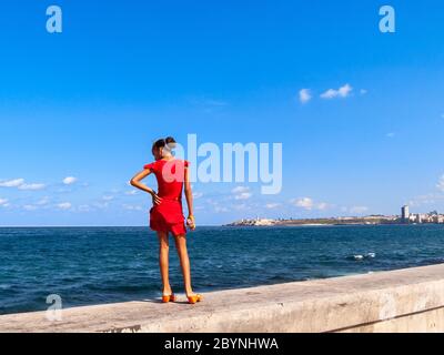 Giovane ragazza che si trova sulle mura di El Malecon, l'Avana, Cuba Foto Stock