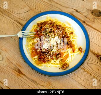 Spaghetti alla bolognese alla italiana con salsa di manzo tritato e pomodoro condito con formaggio e pepe nero su un tavolo di legno Foto Stock